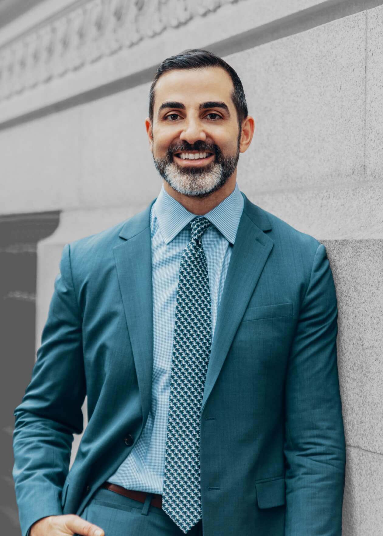 Dr. Sina against a building wall