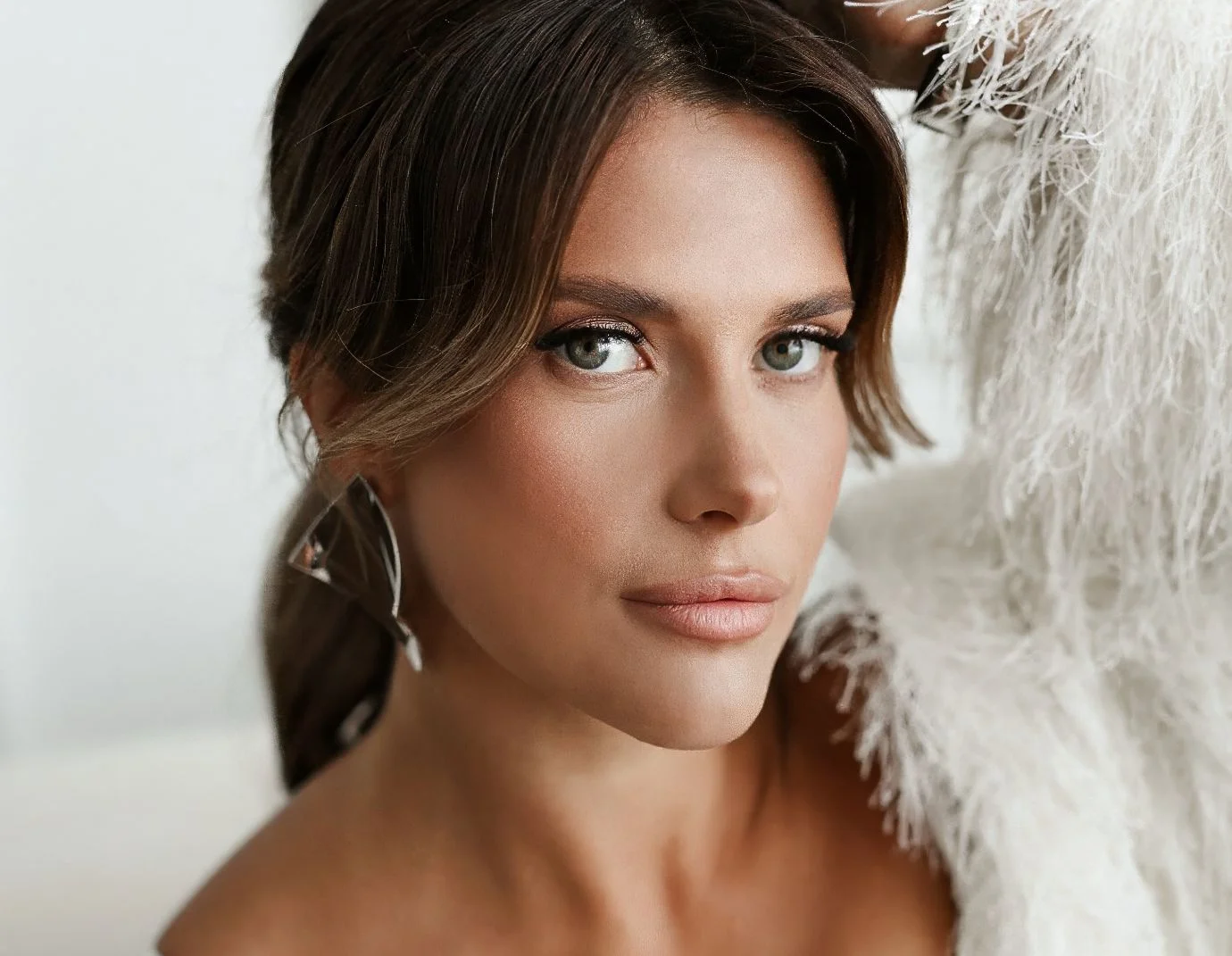 a closeup of a young woman with green eyes and hair pulled back and wavy bangs